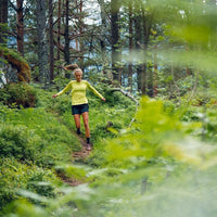 Löpare på en skogsstig i grönskande terräng