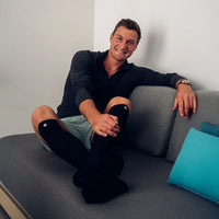 Man sitter i en soffa med svarta Bauerfeind Sports Recovery kompressionsstrumpor